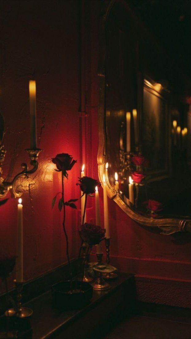 Sala à luz de velas, com candelabros, espelho dourado e rosas vermelhas