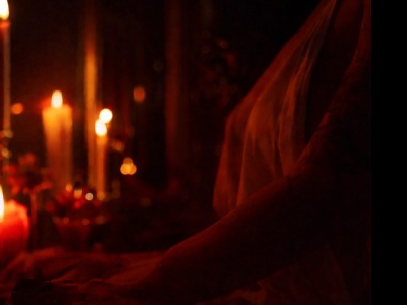 Velas acesas e tecido vermelho em ambiente à meia-luz